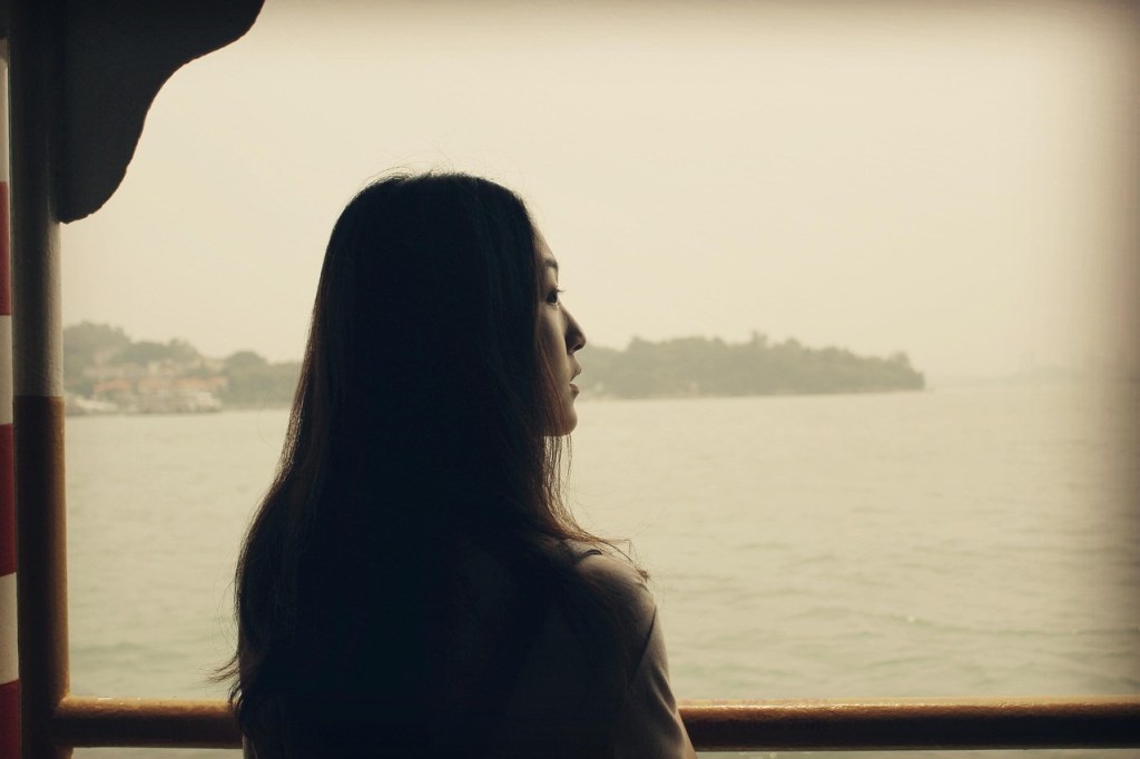 Donna che guarda il paesaggio attraverso una finestra, simbolo di introspezione e consapevolezza interiore