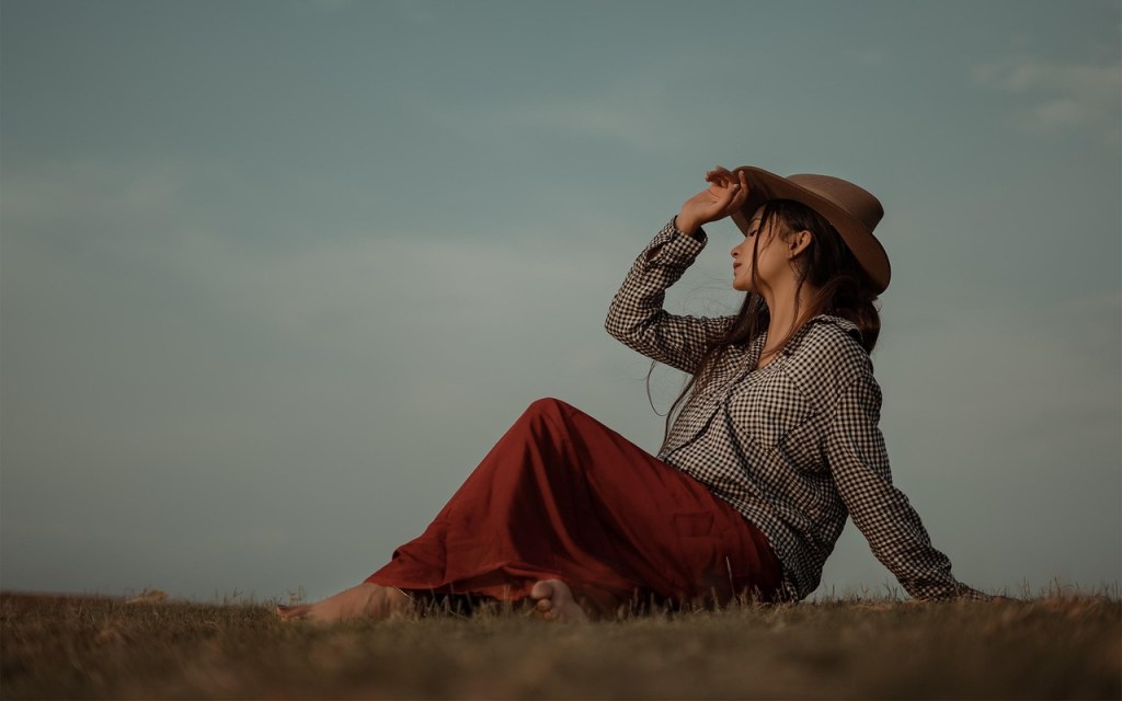 Donna seduta sull’erba che guarda l’orizzonte, simbolo di riconnessione interiore e pace con se stessa