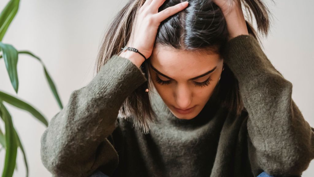 Donna con le mani nei capelli, simbolo di fatica emotiva e blocco motivazionale