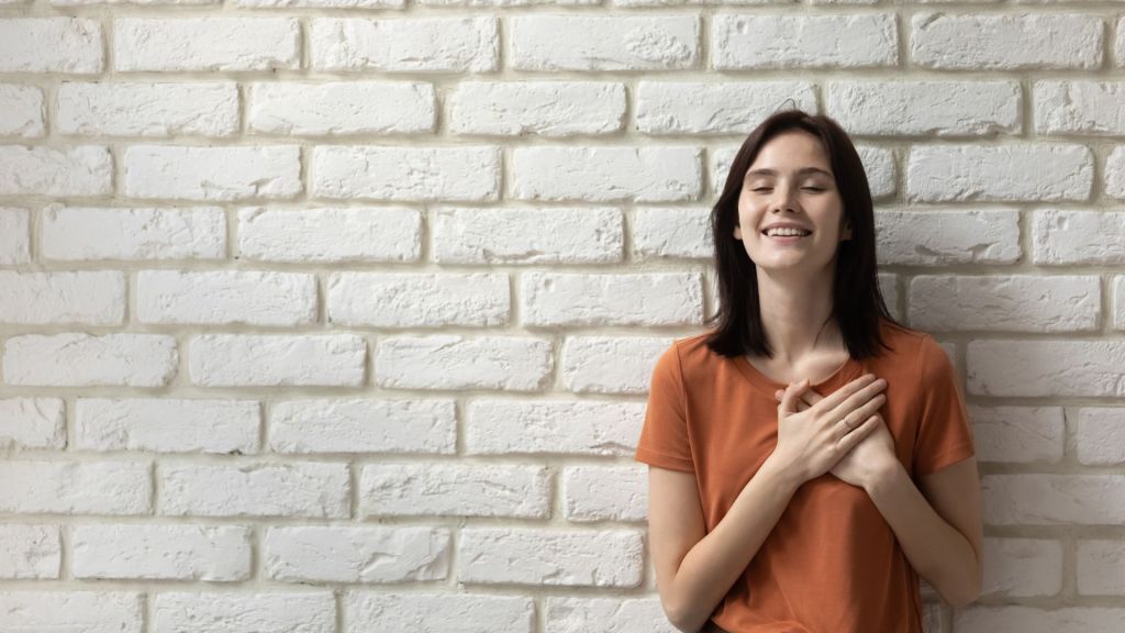 Donna con occhi chiusi e mani sul cuore, in un momento di ascolto interiore e connessione con l’intuizione