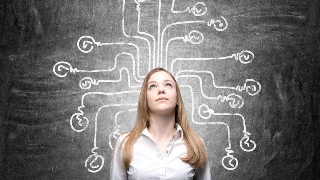 Giovane donna che guarda verso l’alto davanti a un muro con frecce multiple disegnate, simbolo della confusione e della ricerca di direzione